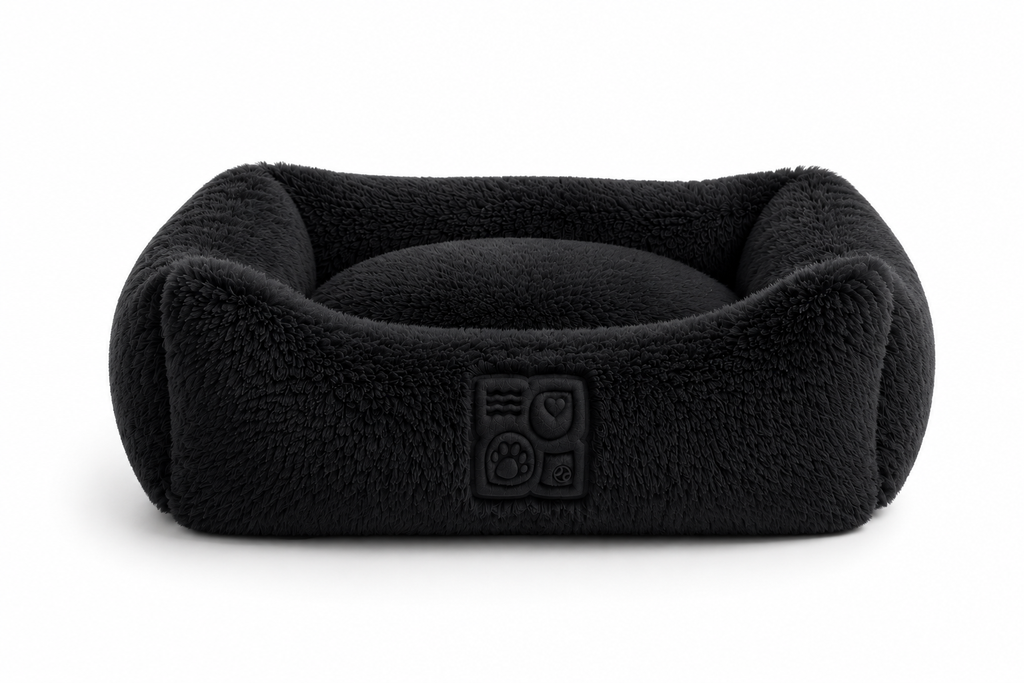 A black, fleece pet bed with a raised edge and cushion on a plain white background